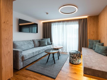 Wohnen mit Stil und Komfort Moderner Wohnbereich mit gemütlichem Sofa, Tagesbett, Holzdetails und Balkonblick.